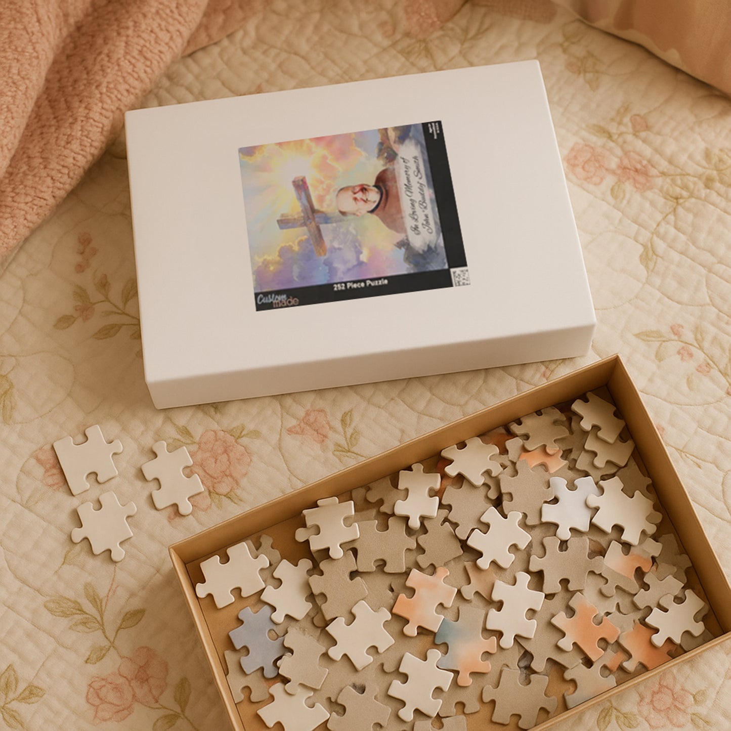 Custom memorial puzzle box with 252 pieces, featuring a sacred cross design and a photo of John "Buddy" Smith, personalized with "In Loving Memory of John 'Buddy' Smith," with pieces inside the box and some scattered on a blanket.