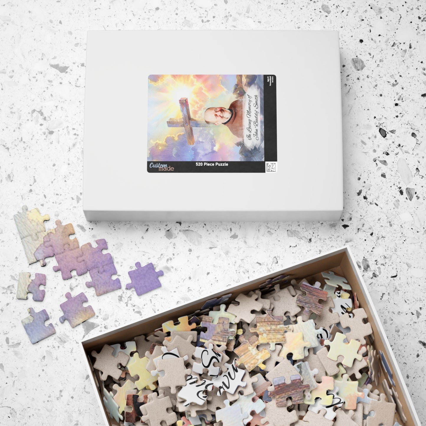 Custom memorial puzzle box with 520 pieces, featuring a sacred design with Jesus and a photo of John Buddy Smith, personalized with "In Loving Memory of John Buddy Smith" with some pieces assembled outside and others inside the box.