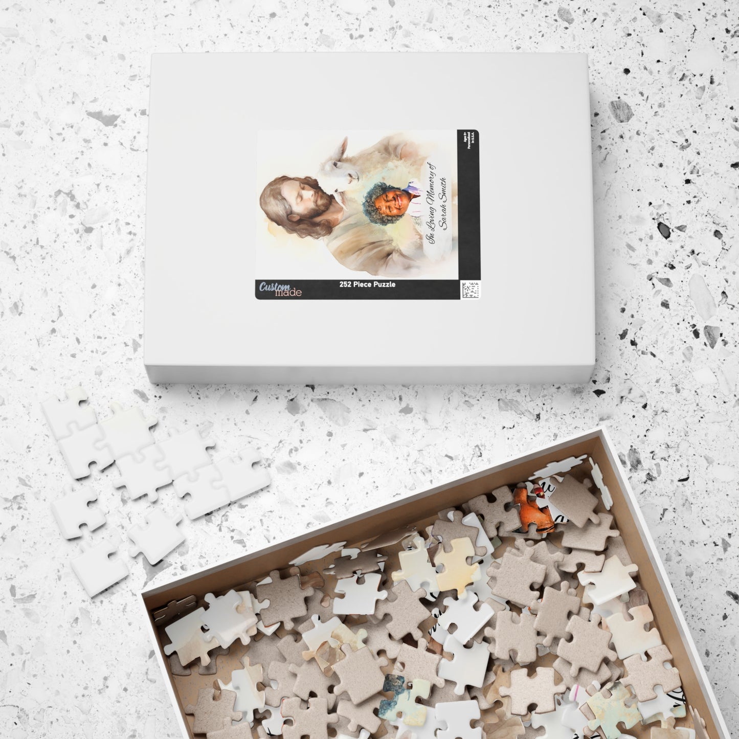 Personalized memorial puzzle box with 252 pieces, featuring a sacred shepherd design with Jesus holding a lamb and a photo of Sarah Smith, personalized with "In Loving Memory of Sarah Smith," with pieces inside the box.