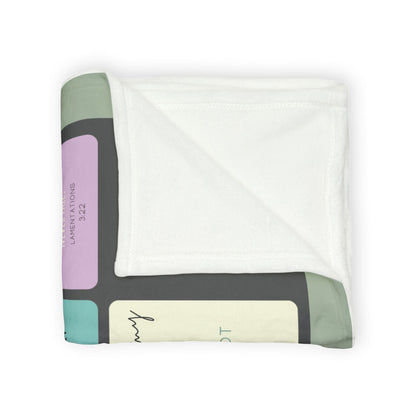 Folded Christian memorial blanket featuring an "In Loving Memory" scripture design with uplifting Bible verses, including a reference to Lamentations 3:22, in soft pastel tones with a cross and dove motif.